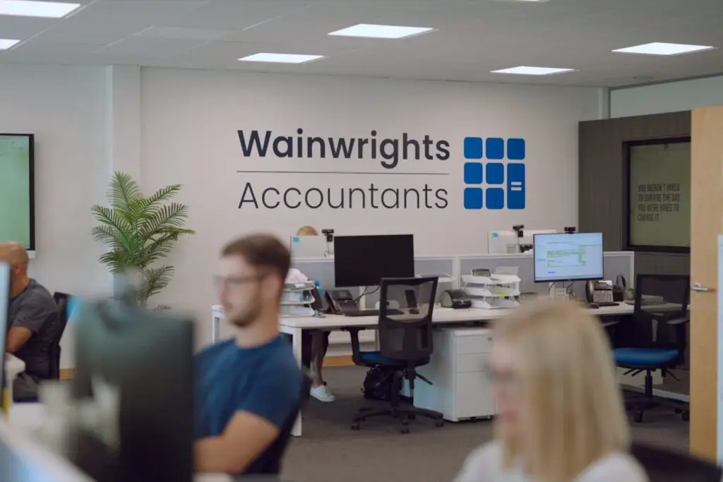 The Wainwrights Accountants logo on the office wall, with the team working at their computers in the foreground