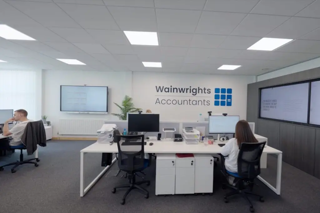 Accountants working at their desks beneath the Wainwrights Accountants logo in the Bromborough office