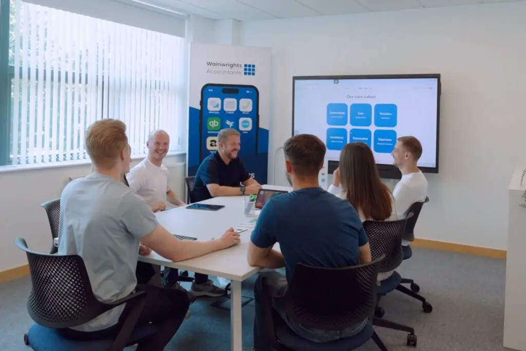 Six members of the Wainwrights Accountants team talking around the meeting room table in Bromborough