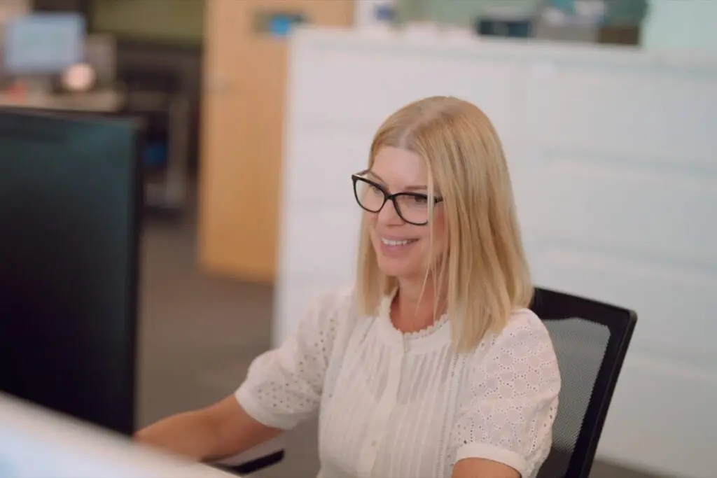 A Wainwrights accountant in glasses smiling as she works at her computer