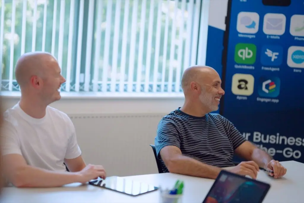Two members of the Wainwrights Accountants team sharing a joke at the meeting room table